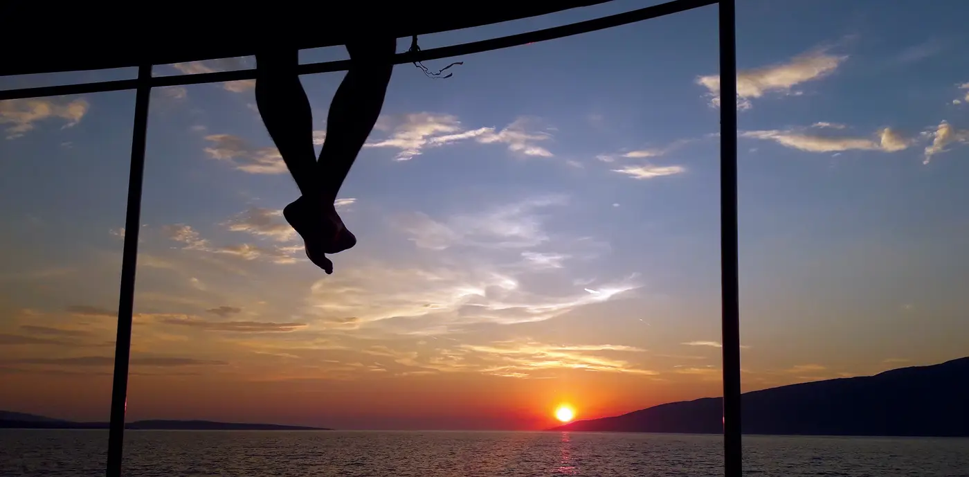 Legs dangling off the boat at sunset