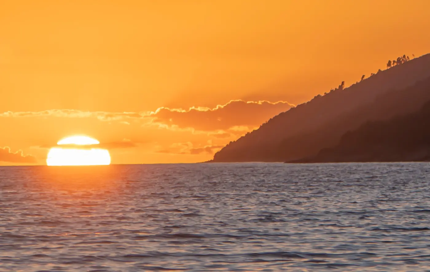 The sun setting over the headland and calm sea