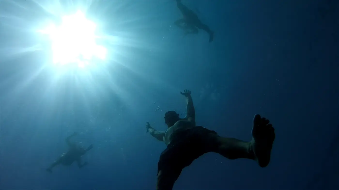 Diver beneath sunrays in clear water